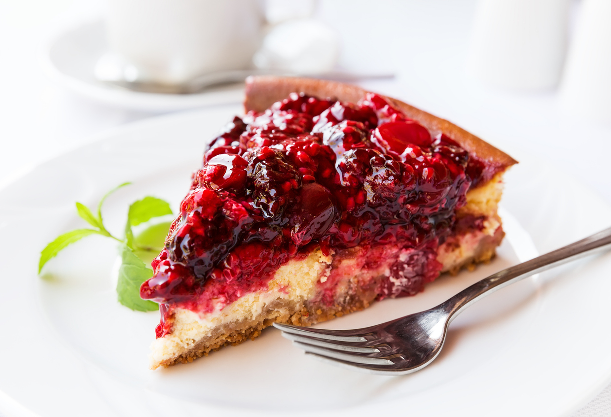 Wild berries cake with green mint on plate with fork. Selective focus